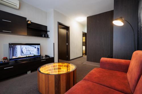 a living room with a couch and a tv at Lucky Bansko Aparthotel SPA & Relax in Bansko