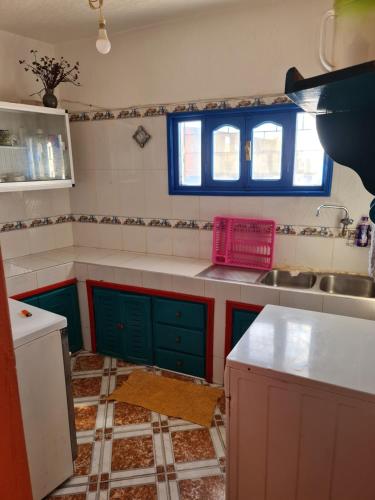 a kitchen with green and blue cabinets and a sink at Maison Banana in Aourir