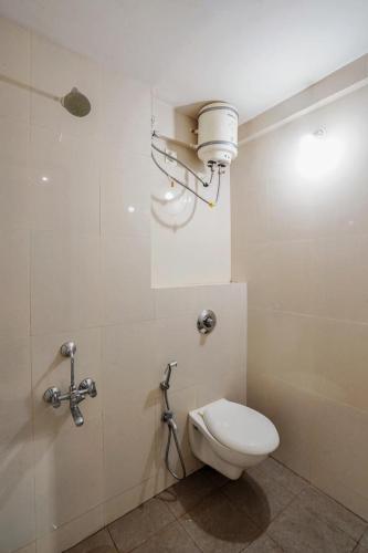a bathroom with a toilet and a light on the wall at Hotel H One in Pune