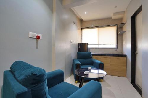 a living room with two blue chairs and a table at Hotel H One in Pune