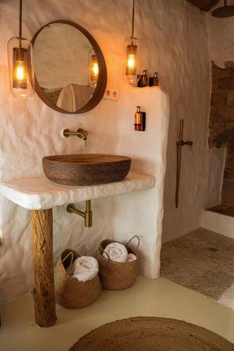 a bathroom with a sink and baskets of towels at Laan Arcos, casa cueva in Arcos de la Frontera