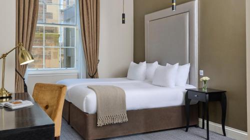 a hotel room with a bed and a desk and a window at Fraser Suites Edinburgh in Edinburgh