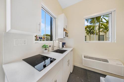 a white kitchen with a sink and a window at El Jardin Inn in Miami
