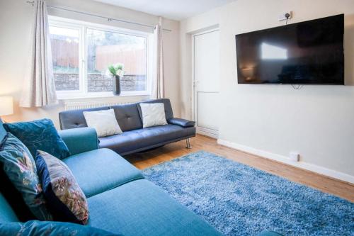 a living room with a blue couch and a flat screen tv at Gellionen - 2 Bedroom House - Clydach in Clydach