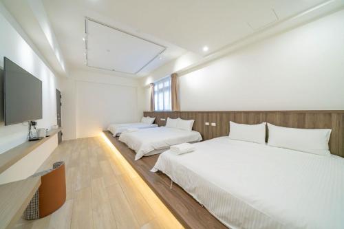 a bedroom with two beds and a flat screen tv at Yunheyue B&B in Suao