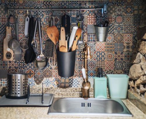 eine Küchenspüle mit Utensilien an einer Wand in der Unterkunft Casa do Azevim in Gavieira