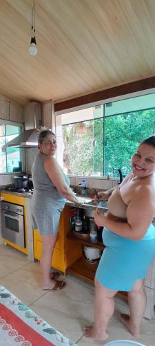 two women standing in a kitchen preparing food at Descanso merecido in Morretes