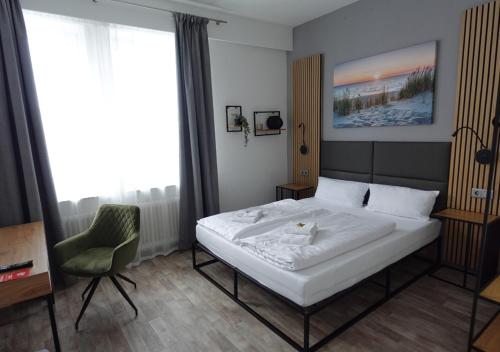 a bedroom with a white bed and a chair at Hotel Handelshof in Bünde