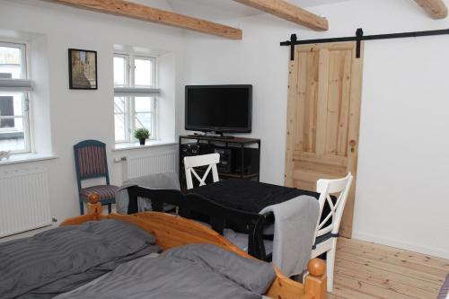 a bedroom with a bed and a tv and a door at 1st floor 2 rooms with kitchenette in Store Heddinge
