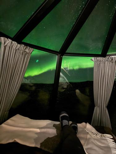 a person laying in a tent looking at the northern lights at Adventure Stay in Vík