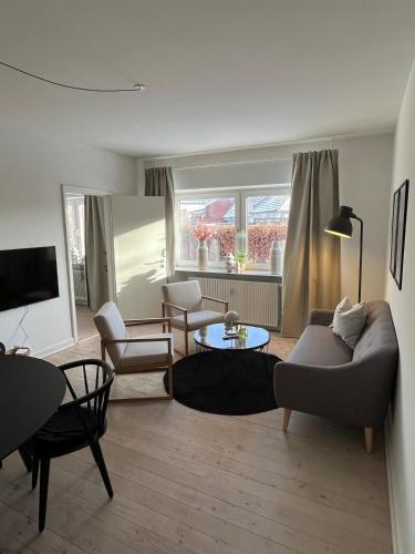 a living room with a couch and chairs and a table at Hyggelig lejlighed tæt på centrum og letbanestop in Odense