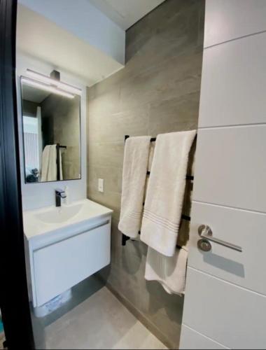 a bathroom with a sink and a mirror and towels at CityNest Hotel Apartment in Cape Town
