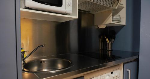 eine Küche mit Spüle und Mikrowelle in der Unterkunft Apartamentos Vértice Sevilla Aljarafe in Bormujos