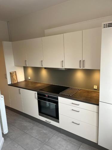 a kitchen with white cabinets and a stove top oven at Hyggelig lejlighed tæt på centrum og letbanestop in Odense
