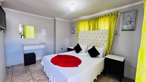 a bedroom with a white bed with a red flower on it at Village Boiketlo in Bloemfontein