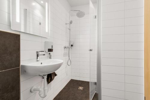 ein weißes Badezimmer mit Waschbecken und Dusche in der Unterkunft Hotel Vellir in Hafnarfjördur