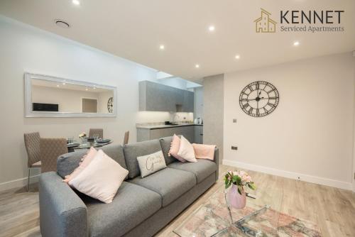 a living room with a gray couch and a kitchen at Chester House in Reading