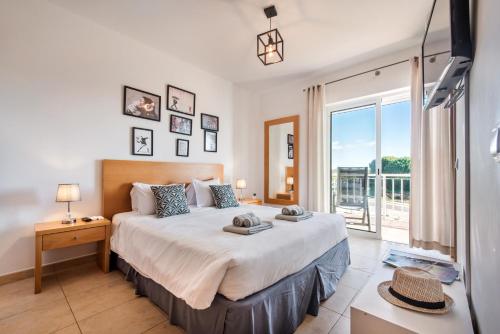a bedroom with a large bed and a large window at Casa Louro in Cabanas de Tavira