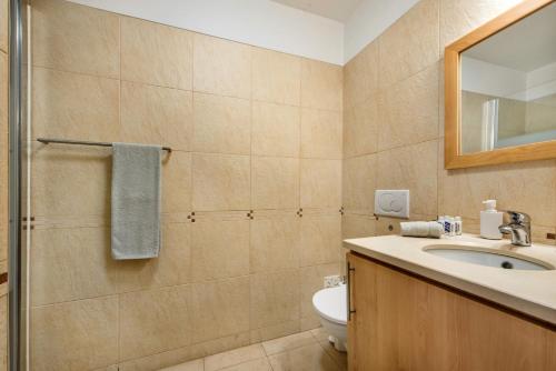 a bathroom with a sink and a toilet and a mirror at Casa Louro in Cabanas de Tavira