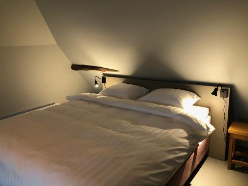 a bedroom with a bed with white sheets and pillows at B&B en theetuin Loodiep in Zwinderen