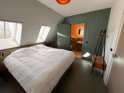 a bedroom with a large bed and a bathroom at B&B en theetuin Loodiep in Zwinderen