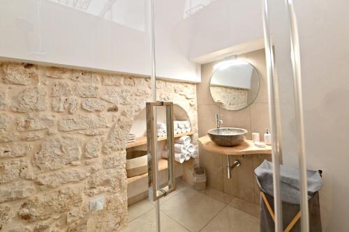 a bathroom with a sink and a stone wall at Almurigini I Boutique House I Ceglie Messapica in Ceglie Messapica