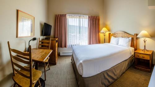 a hotel room with a bed and a table and a desk at Cahilty #434 home in Sun Peaks