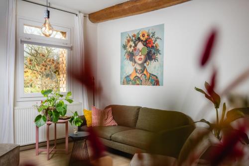 a living room with a couch and a painting on the wall at Hoeve de Binnenplaets - Appartementen - Glamping - Familieverblijf in Schimmert