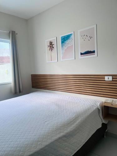 a bedroom with a large white bed with pictures on the wall at Pool house próximo ao centro in Matinhos