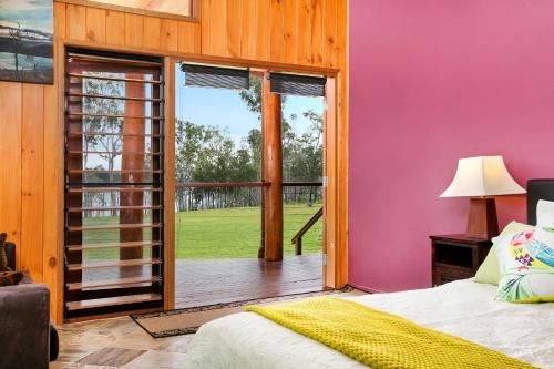 a bedroom with a pink wall and a sliding glass door at Lake Tinaroo Waterfrontage in Barrine