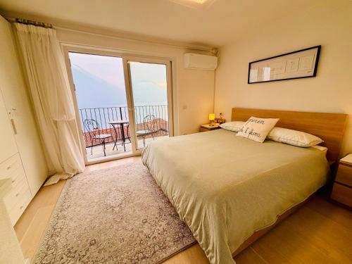 a bedroom with a large bed and a large window at Argegno Pool apartment by Italian Apartments in Argegno