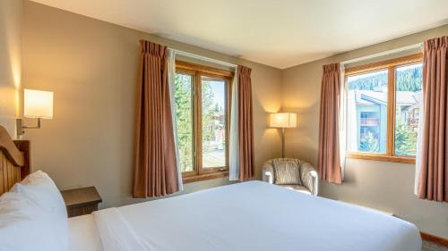 a bedroom with a white bed and two windows at Cahilty #265 in Sun Peaks
