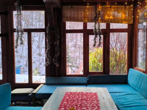 a room with a couch and a table and windows at Traditional Cottage - Vila Samovila in Delčevo
