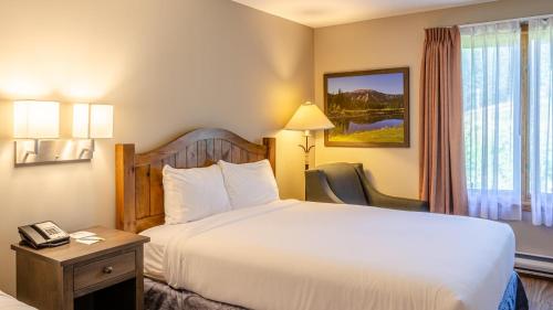a hotel room with a bed and a desk with a phone at Cahilty #313 home in Sun Peaks