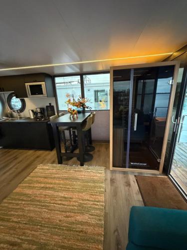 a living room with a table and a kitchen at Exclusieve Houseboat La Mare 12 x 5 meter met sauna en hottup in Maasbommel