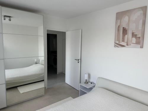 a white bedroom with a mirror and a bed at Appartement de standing, parking privé, climatisé, proche du centre-ville et la gare centre in Avignon