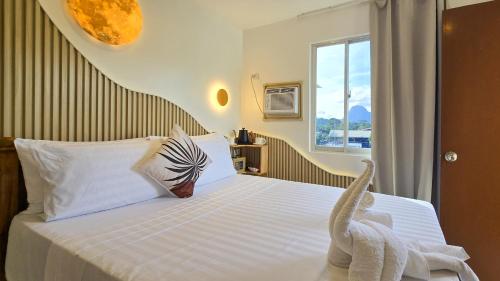 a bedroom with a bed with white sheets and a window at SilverLeaf in El Nido
