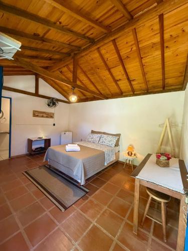 a bedroom with a bed and a table in it at Pousada chalés São Geraldo in Lima Duarte