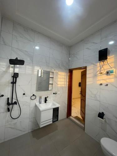 a white bathroom with a sink and a shower at JudEls SA Guest House in Accra