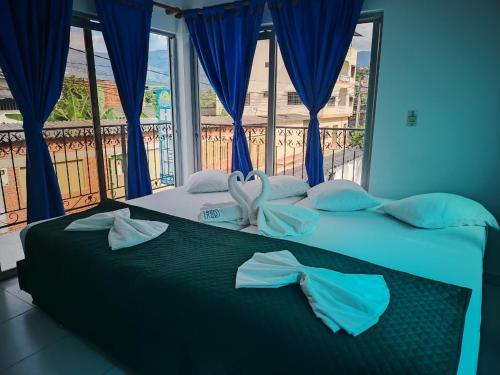 a bedroom with a bed with blue curtains and a window at Hotel Los Delfines Melgar in Melgar
