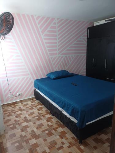 a bedroom with a blue bed and a pink wall at Apartamento Aboleda Campestre in Ibagué
