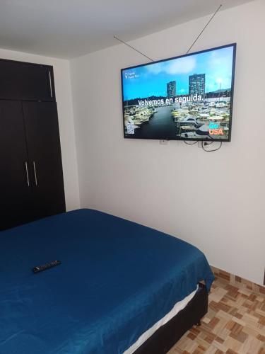 a bedroom with a bed and a tv on the wall at Apartamento Aboleda Campestre in Ibagué