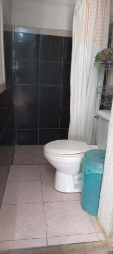 a bathroom with a toilet and a black tiled wall at Hostel Casa María in Masaya