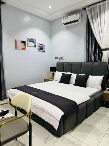 a bedroom with a large bed and a chair at Flora By Bibaley Hotel in Kaduna