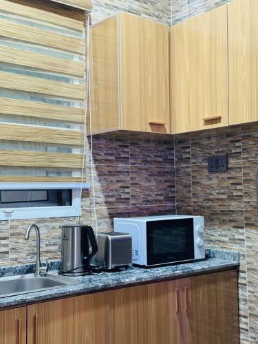 a kitchen counter with a microwave and a sink at Flora By Bibaley Hotel in Kaduna