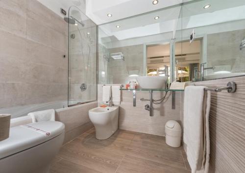 a bathroom with a toilet and a tub and a sink at Acacia Resort in Campofelice di Roccella