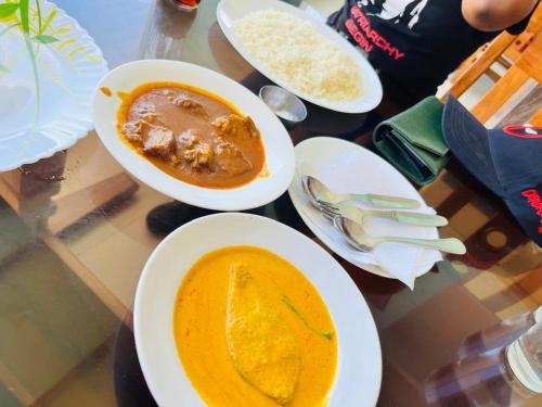 a table with plates of food and a bowl of soup at Pebbles Guest House Digha in Digha