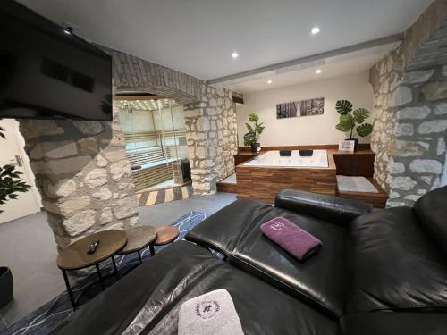 a living room with a leather couch and a bath tub at Appart Spa Privatif in Reims
