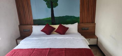 a bedroom with a bed with red and white pillows at Karmalhills Homestay in Tindummal
