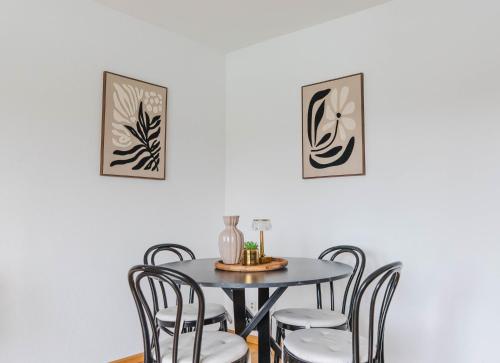 a dining room table and chairs with two pictures on the wall at Dreiländer-Blick Apartment 2 Schlafzimmer in Lörrach